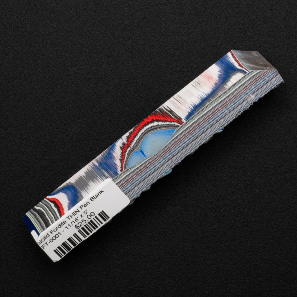Solid Fordite pen blank FT-0001 displaying layered blue, red, white and gray bands from decades of automotive paint overspray